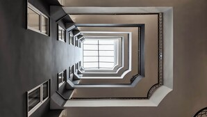 A modern interior with a central skylight, geometric wall design, and a minimalist staircase. - Kaila City Hotel (Alanya)
