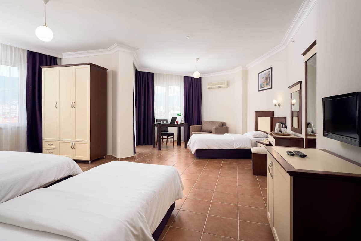 A hotel room with two beds, a desk, a TV, and a wardrobe.