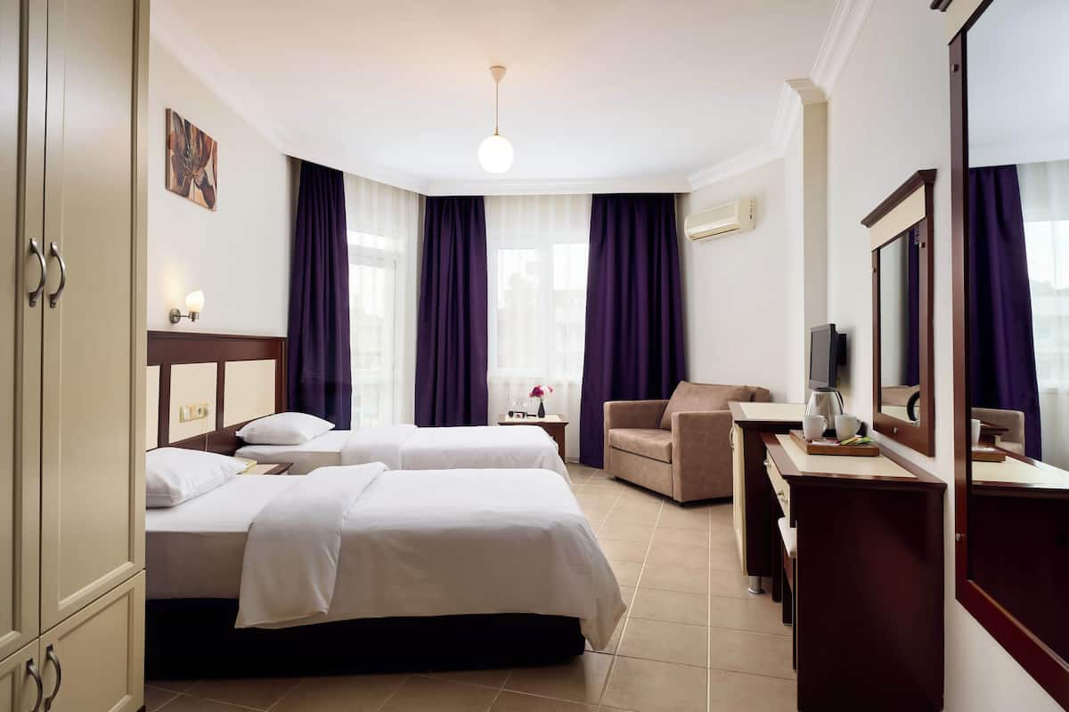 A hotel room with two beds, a desk, a chair, a TV, and a large mirror.