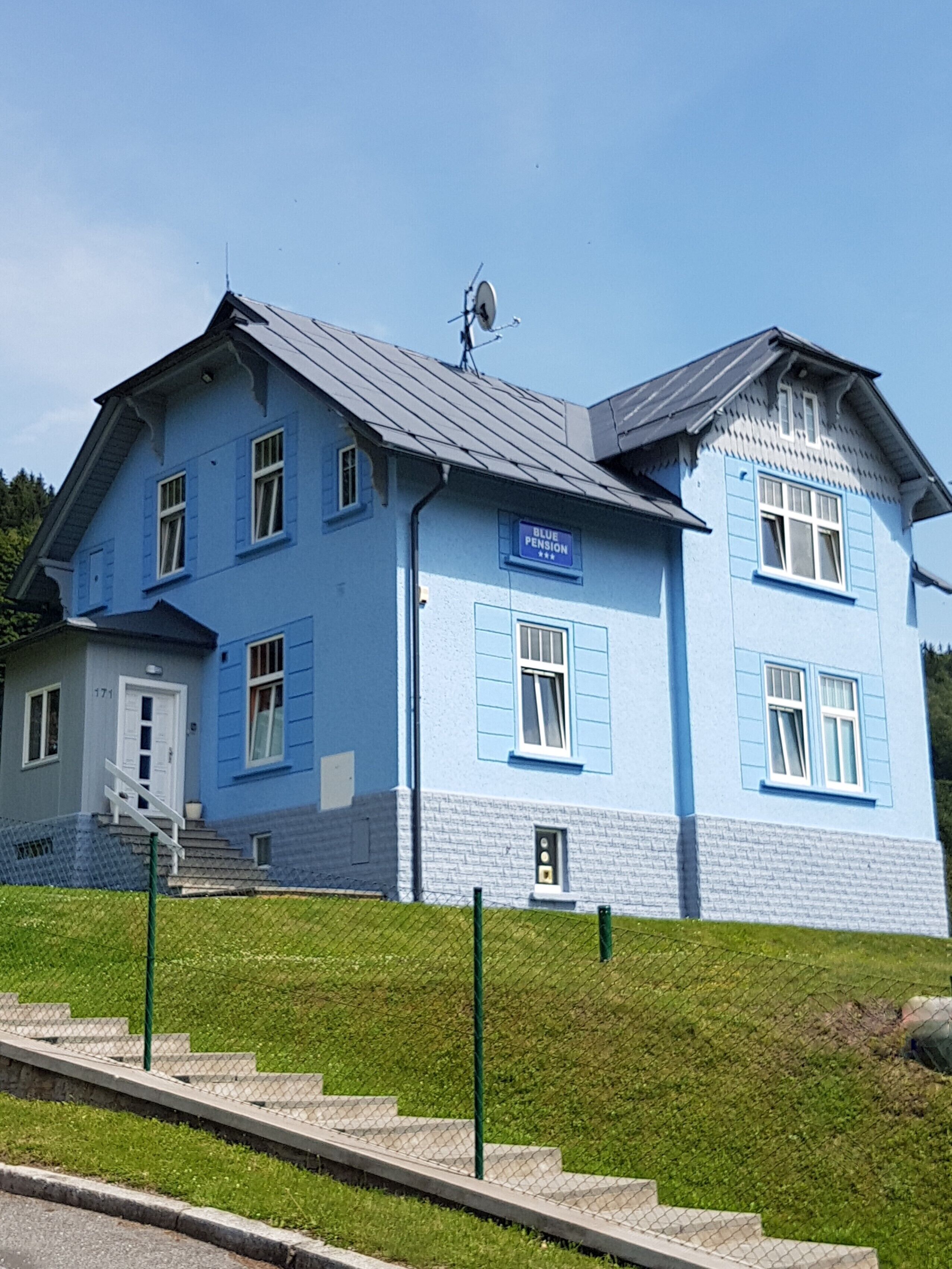 Un edificio de dos pisos con fachada azul y un letrero que dice 'Blue Pension'.