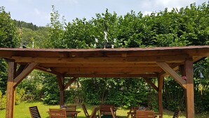 Una pérgola de madera con una mesa y sillas dispuestas debajo.