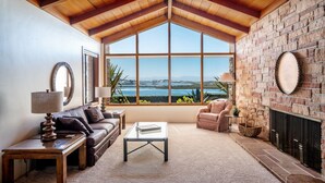 A spacious living room with a high ceiling, large windows offering a view of the sea, a fireplace, and a cozy seating area. - Capurro Ranch at Moss Landing - Moss Landing House - 5BR with cottage at Elkhorn Slough (Moss Landing)