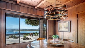 A wooden-paneled room with a large window overlooking a beach and ocean. - Capurro Ranch at Moss Landing - Moss Landing House - 5BR with cottage at Elkhorn Slough (Moss Landing)