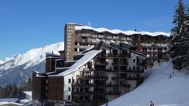 A multi-story ski resort building with balconies and a ski slope in the foreground. - Cozy T3 for 6 people in center with ski-in/ski-out, parking (La Tania)