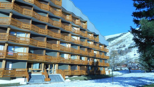 A multi-story hotel with wooden balconies and a ski slope in the background. - Studio for 4 at slopes, center Les Deux Alpes (Les Deux Alpes)