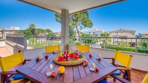 Una mesa de madera con sillas amarillas en un balcón que ofrece vistas despejadas a edificios y árboles.