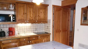 A kitchen with wooden cabinets, a microwave, a coffee maker, and a table with chairs. - 3-room apt for 4, balcony, pets welcome in Allues (Méribel)