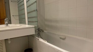 A bathroom with a white sink, mirror, and bathtub. - Cozy apartment in Méribel for 4 pers., close to amenities (Méribel)