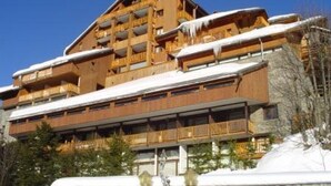 A multi-story wooden building with balconies, surrounded by snow. - 5-room duplex for 10 people in Méribel, pets allowed (Méribel)
