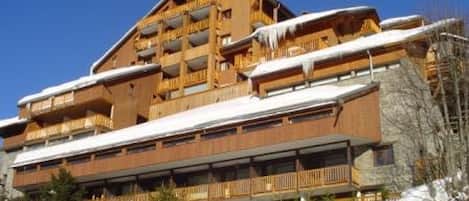 A multi-story wooden building with balconies, surrounded by snow.
