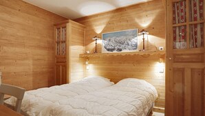 A wooden cabin bedroom with a bed, a nightstand, a lamp, and a painting on the wall. - 5-room duplex for 10 people in Méribel, pets allowed (Méribel)