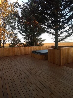 Terraza de madera con jacuzzi y valla de madera.