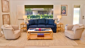 A living room with a sofa, two armchairs, a coffee table, and a view of greenery outside. - Ma'alaea Surf, Unit E1-2 BR Ground Floor Beachfront Condo, AC, Wifi, Pool (Kihei)