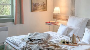 Un lit bien fait, avec des oreillers, une table de chevet avec une lampe et deux tableaux encadrés accrochés au mur.