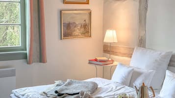 Un lit bien fait, avec des oreillers, une table de chevet avec une lampe et deux tableaux encadrés accrochés au mur.