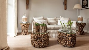 A cozy bedroom with a bed, two nightstands with decorative lamps, and a glass coffee table with plants. - Hotel Sylter Zollhaus (Sylt)