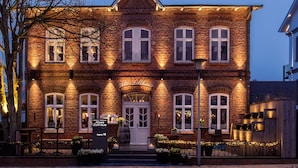 A brick building with a white door and multiple windows, featuring outdoor seating and a sign that reads "Altes Rathaus." - Hotel Sylter Zollhaus (Sylt)
