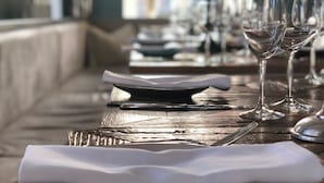 A long dining table with neatly set plates, cutlery, and wine glasses, suggesting a formal dining setting. - Hotel Sylter Zollhaus (Sylt)