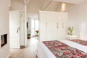 A bedroom with a bed, white wardrobe, and a small table with a vase. - Hotel Sylter Zollhaus (Sylt)