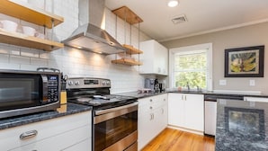 A modern kitchen with white cabinets, stainless steel appliances, and wooden flooring. - 1BR Sparkling Clean Apartment, KING Bed (Winston-Salem)
