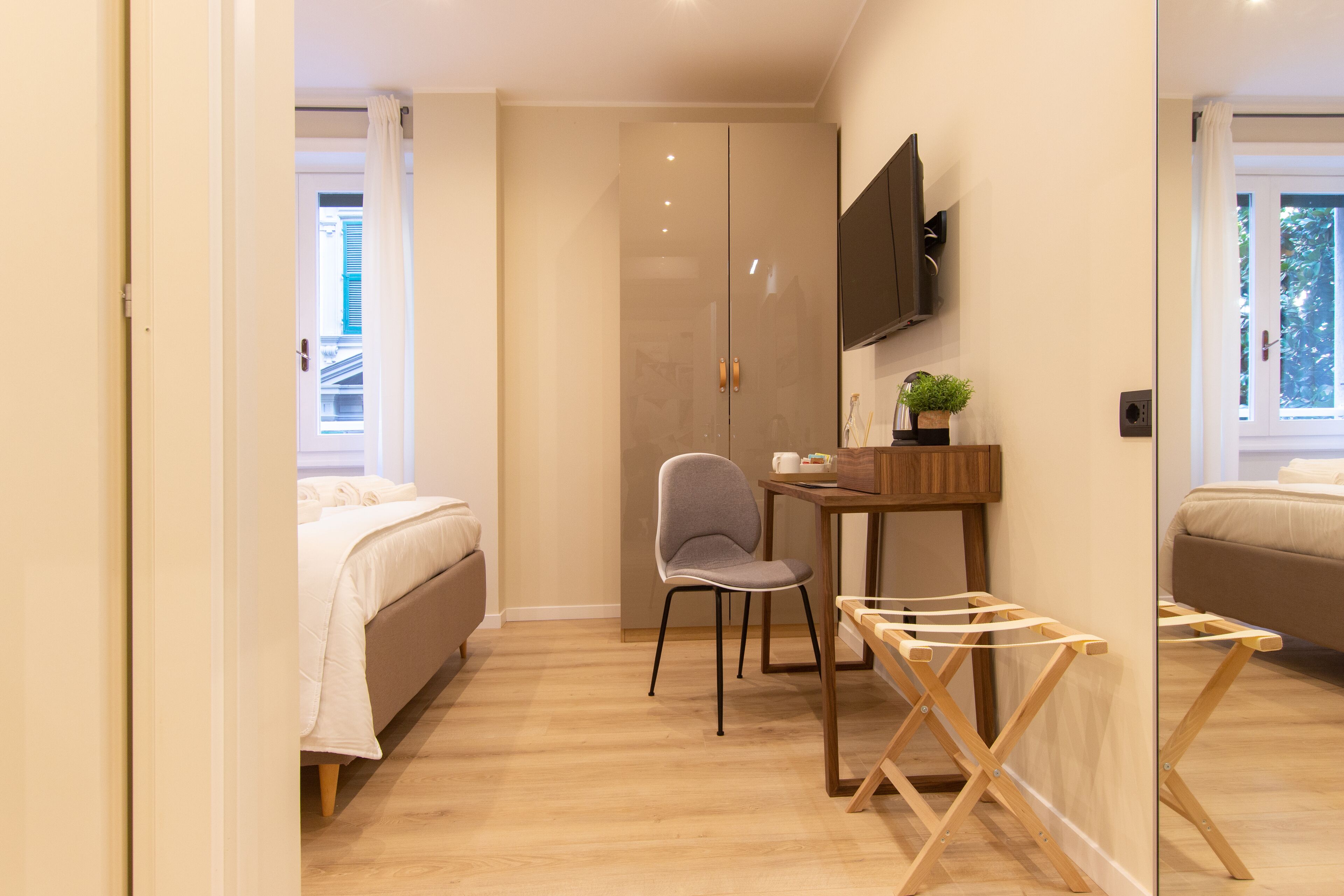 Una habitación de hotel moderna con una cama, un escritorio con silla, un televisor y una ventana.