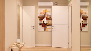 Un pasillo con suelo de madera, puertas blancas y un equipo de aire acondicionado instalado en la pared.