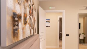 Habitación de hotel con cama, un cuadro en la pared, una puerta que da a un pasillo y un cartel en la pared.