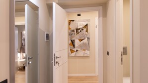 Un pasillo con un cuadro abstracto moderno en la pared, suelo de madera y puertas blancas.