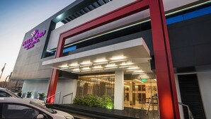 A modern hotel entrance with a prominent neon sign, a glass facade, and a red and white color scheme. - Boudl Al Wadi (Riyadh)