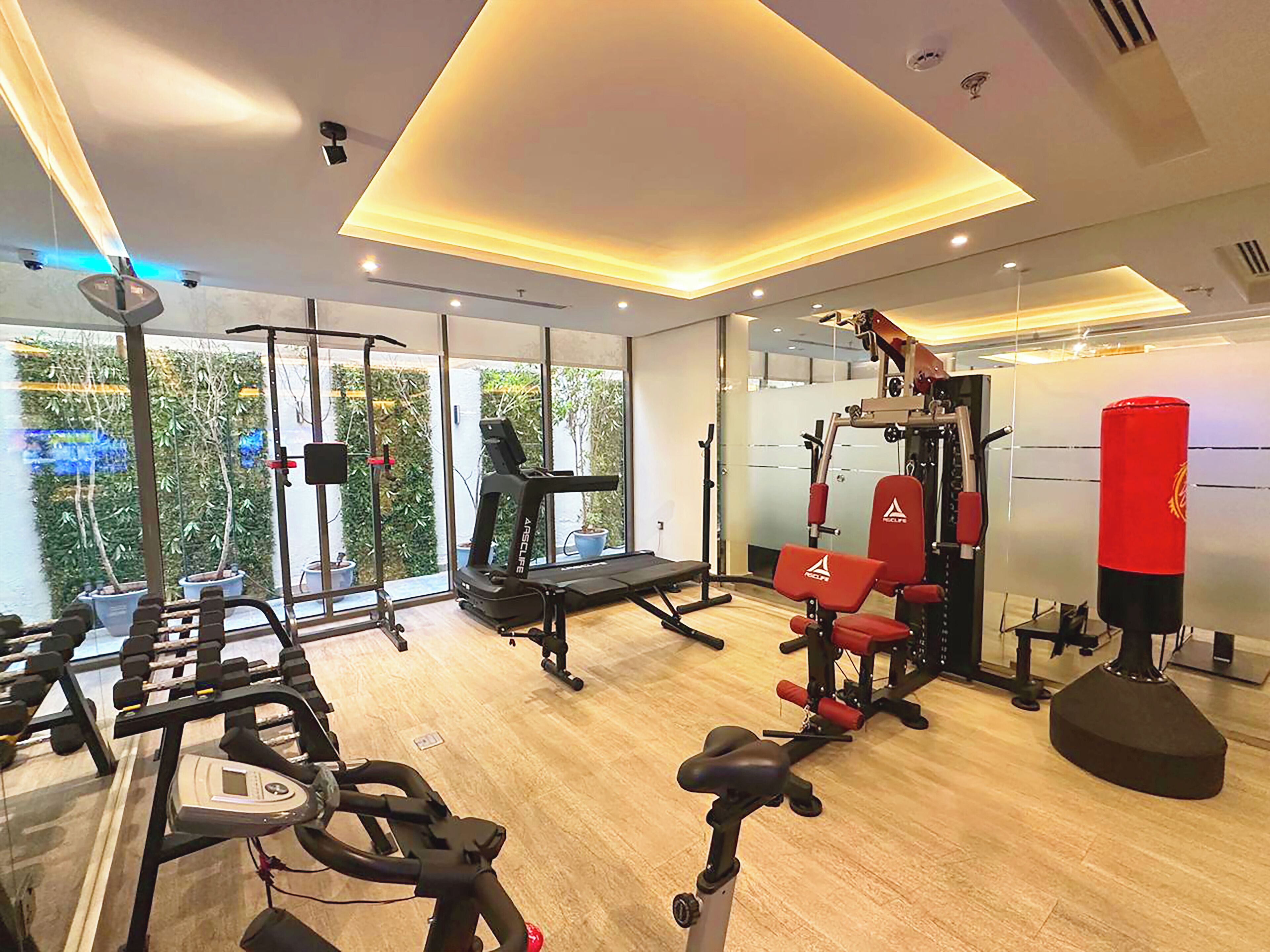 A modern gym with cardio equipment, weight machines, and a punching bag.
