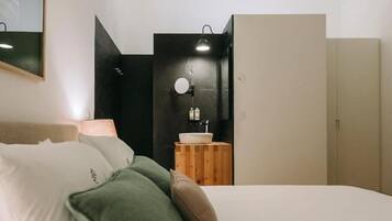 Un dormitorio con una cama, una mesita de noche con lámpara, un espejo y un armario.