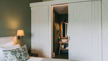 A bedroom with a bed, a nightstand, a lamp, a pillow, and a wardrobe.