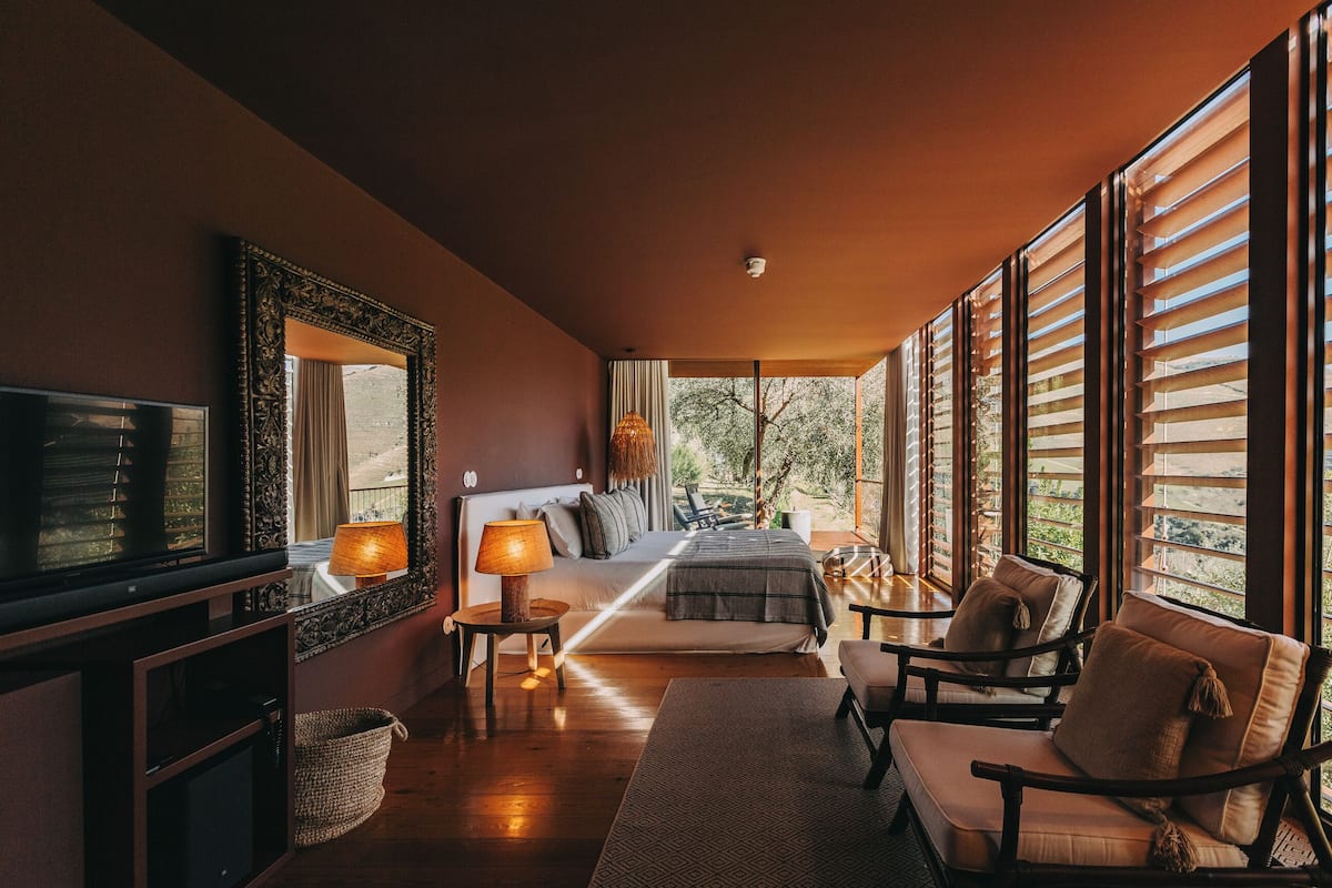 Una habitación amplia con una cama grande, televisión y una zona de estar con sillas y una mesa.