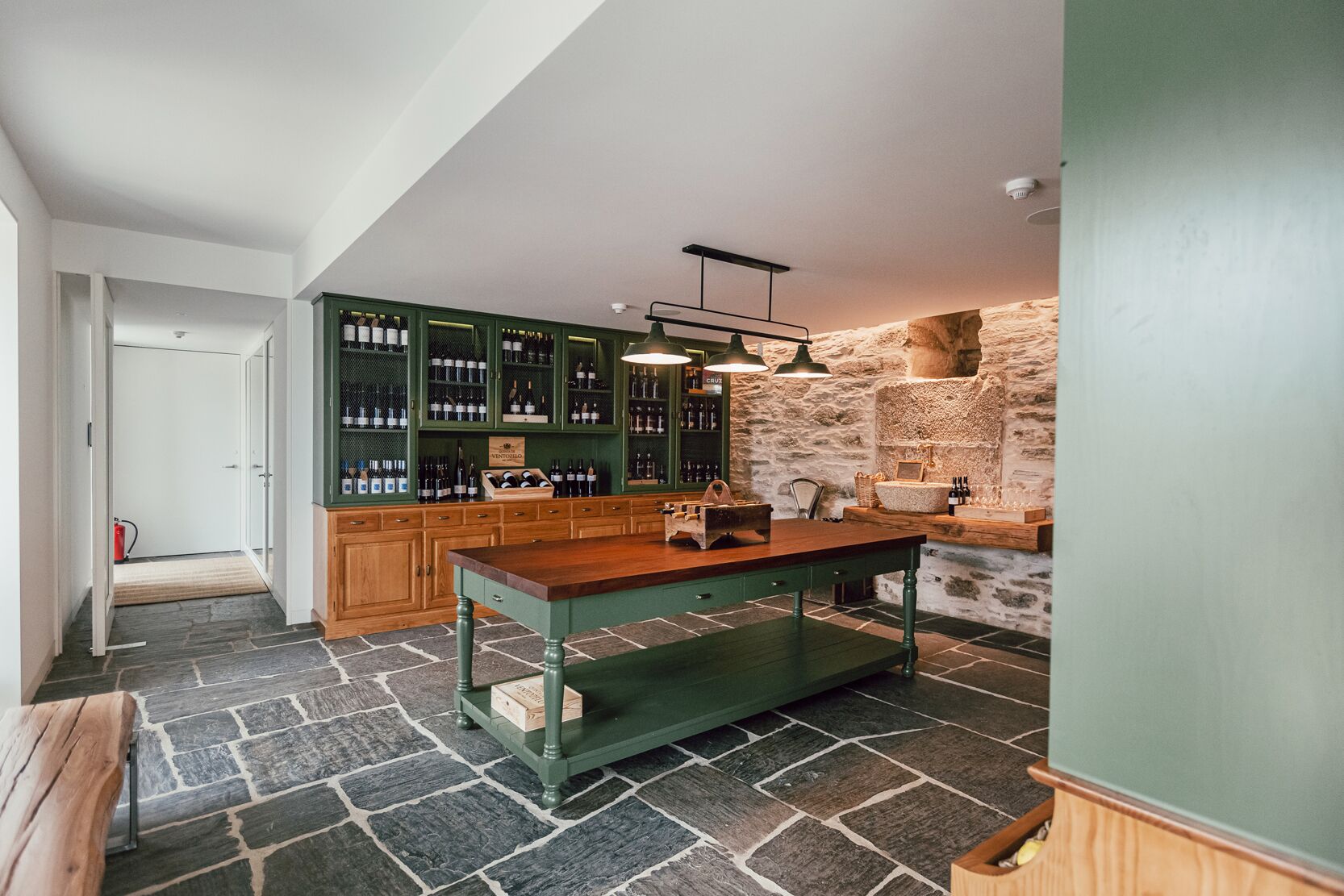 Una cocina con pared de piedra, armarios de madera y una isla central.