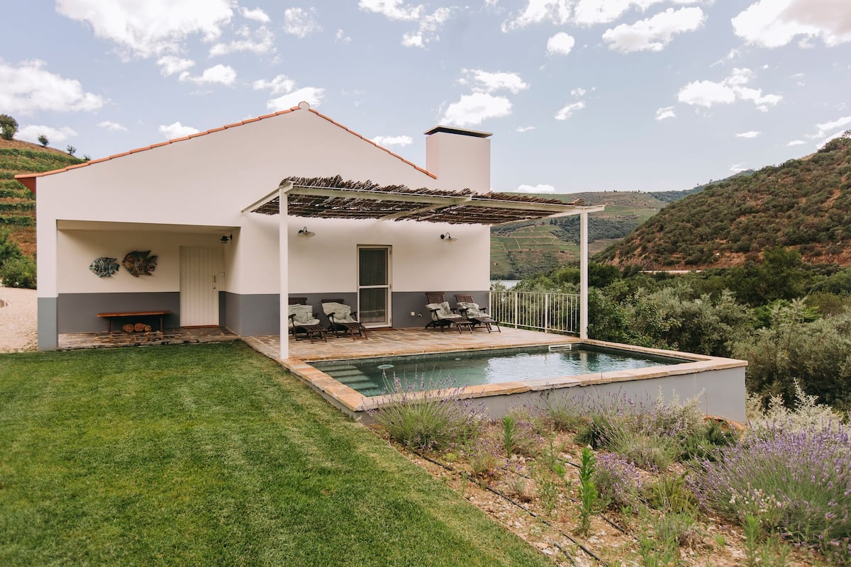Una casa moderna con piscina, un patio cubierto y vistas de las colinas circundantes.