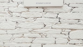 Een bordje voor Cantina De VentoZero, een restaurant en wijnbar, bevestigd aan een witte bakstenen muur.