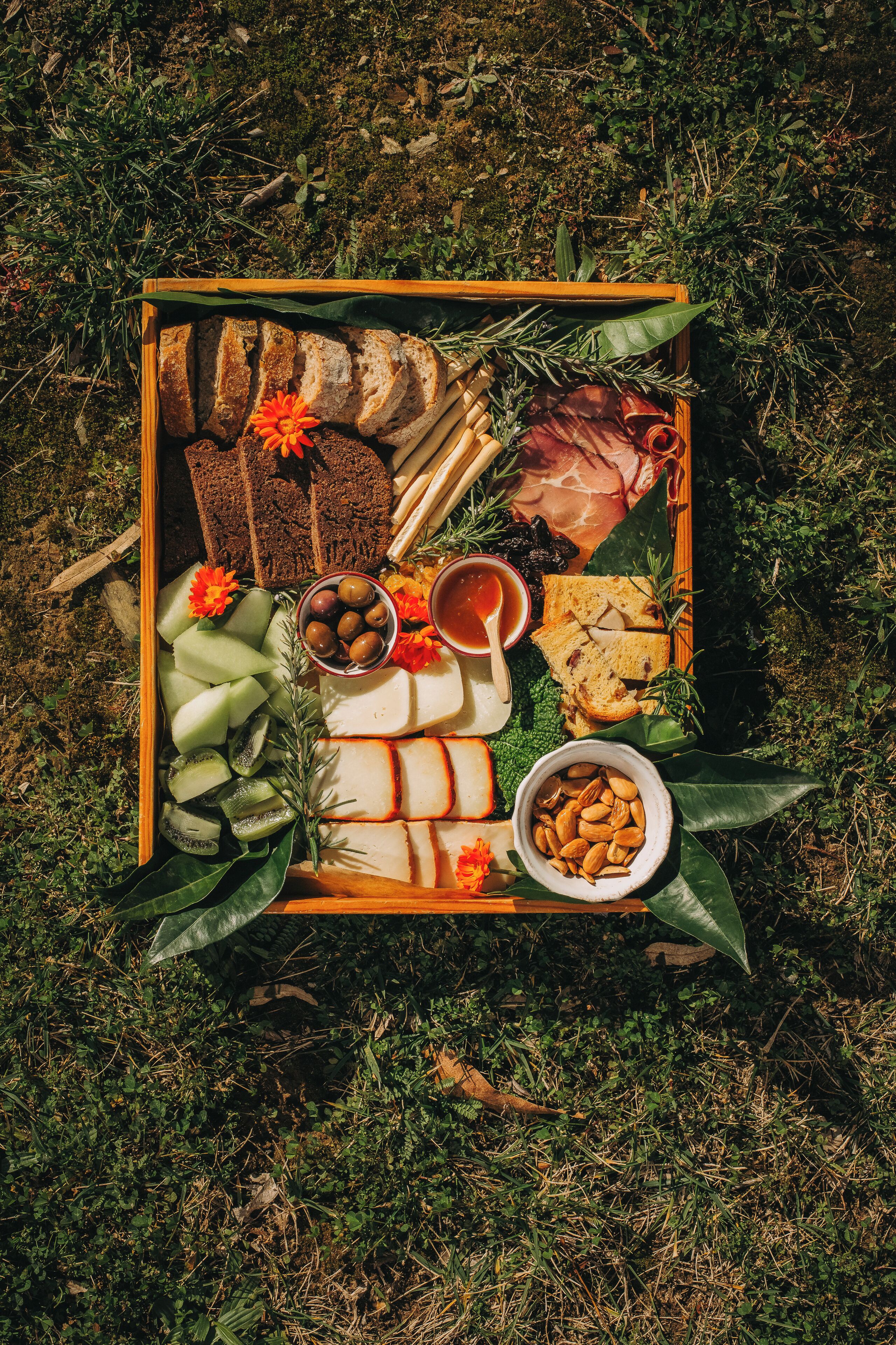 Eine Platte mit verschiedenen Käsesorten, Wurstwaren, Früchten und Nüssen auf einem Holzboden.