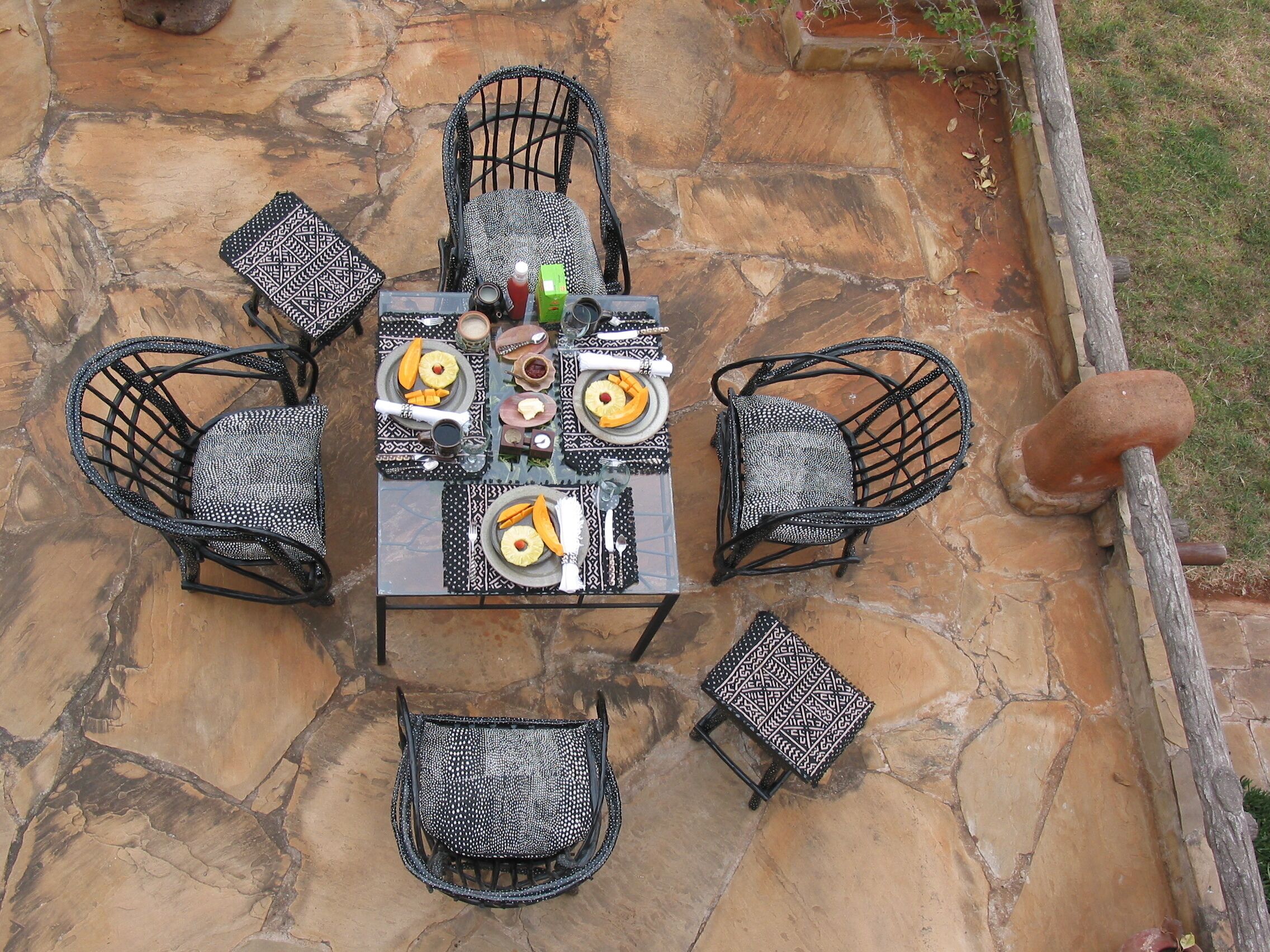 A stone patio with a table set for four, surrounded by four chairs.