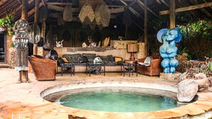 A traditional outdoor seating area with a pool, wicker furniture, and stone statues. - African Heritage House (Mlolongo)