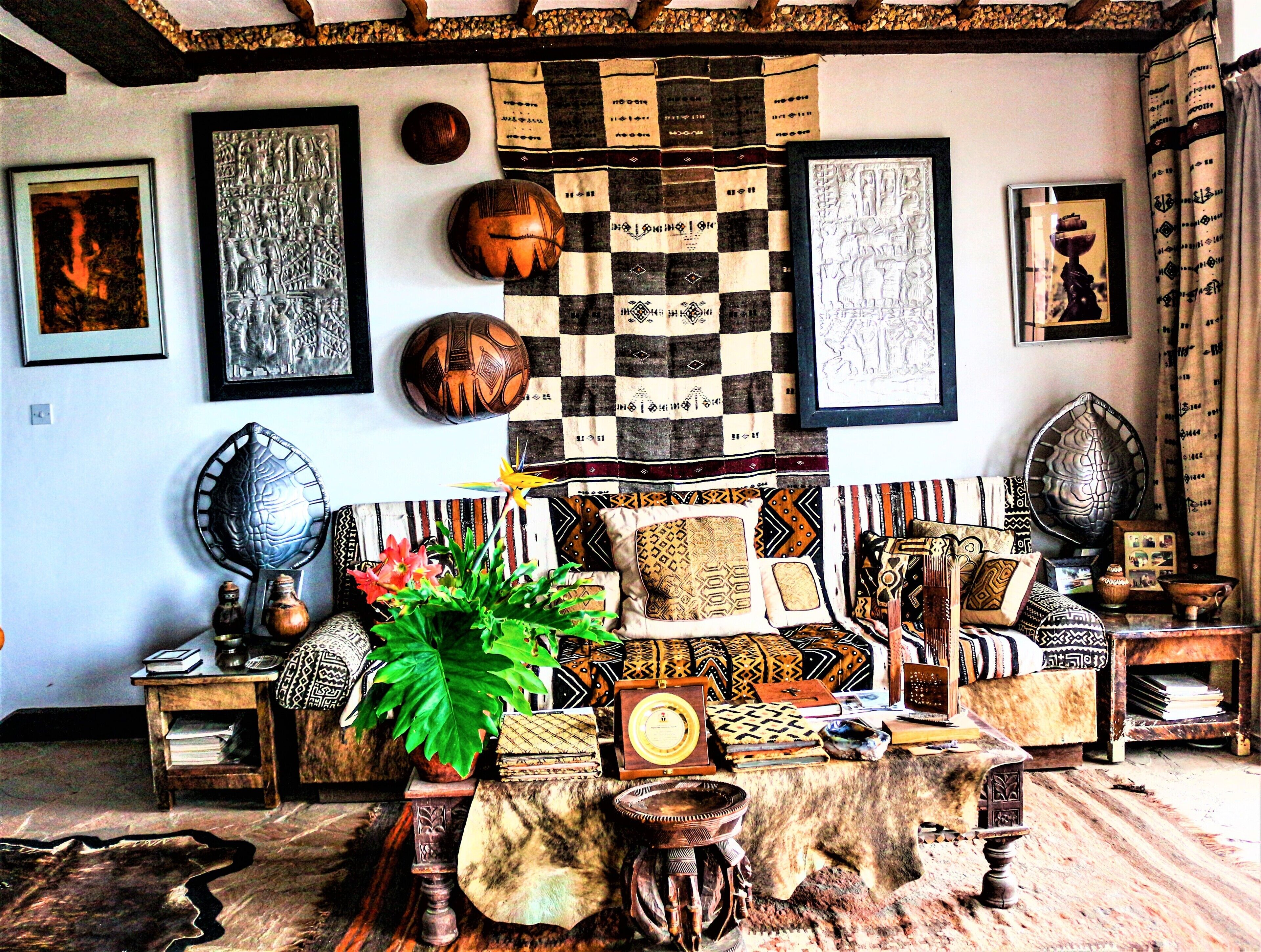 Una habitación con un sofá a cuadros, una planta en maceta y diversos objetos decorativos en las paredes y el suelo.
