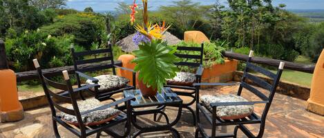 A patio with a table and four chairs, surrounded by lush greenery and a scenic view.