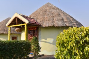 A traditional thatched-roof house with a small porch and a door with colorful trim.