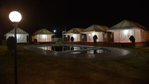 A row of tents with a swimming pool in the center. - Rann Village Resort (Bhuj)