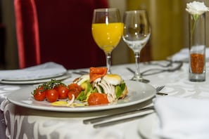 Uma mesa de jantar com um prato de comida, dois copos de suco de laranja e um copo de água.