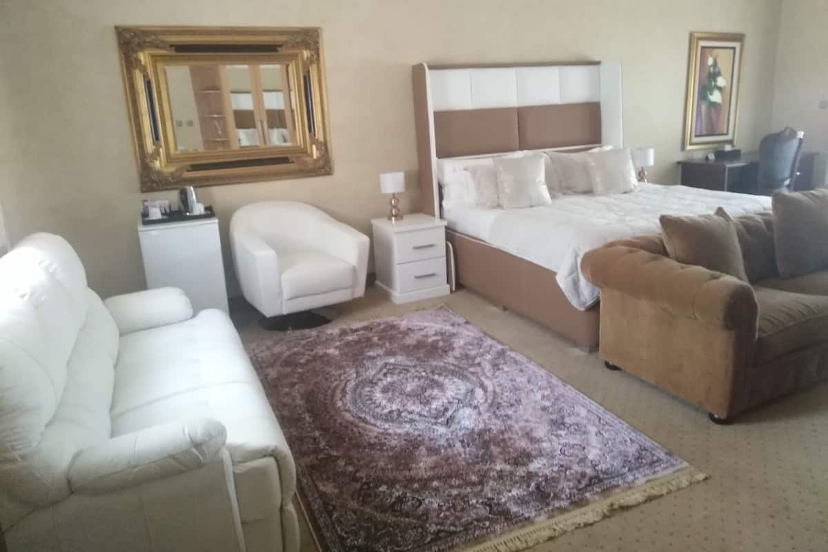 A bedroom with a bed, two chairs, a nightstand, a dresser, and a large rug.