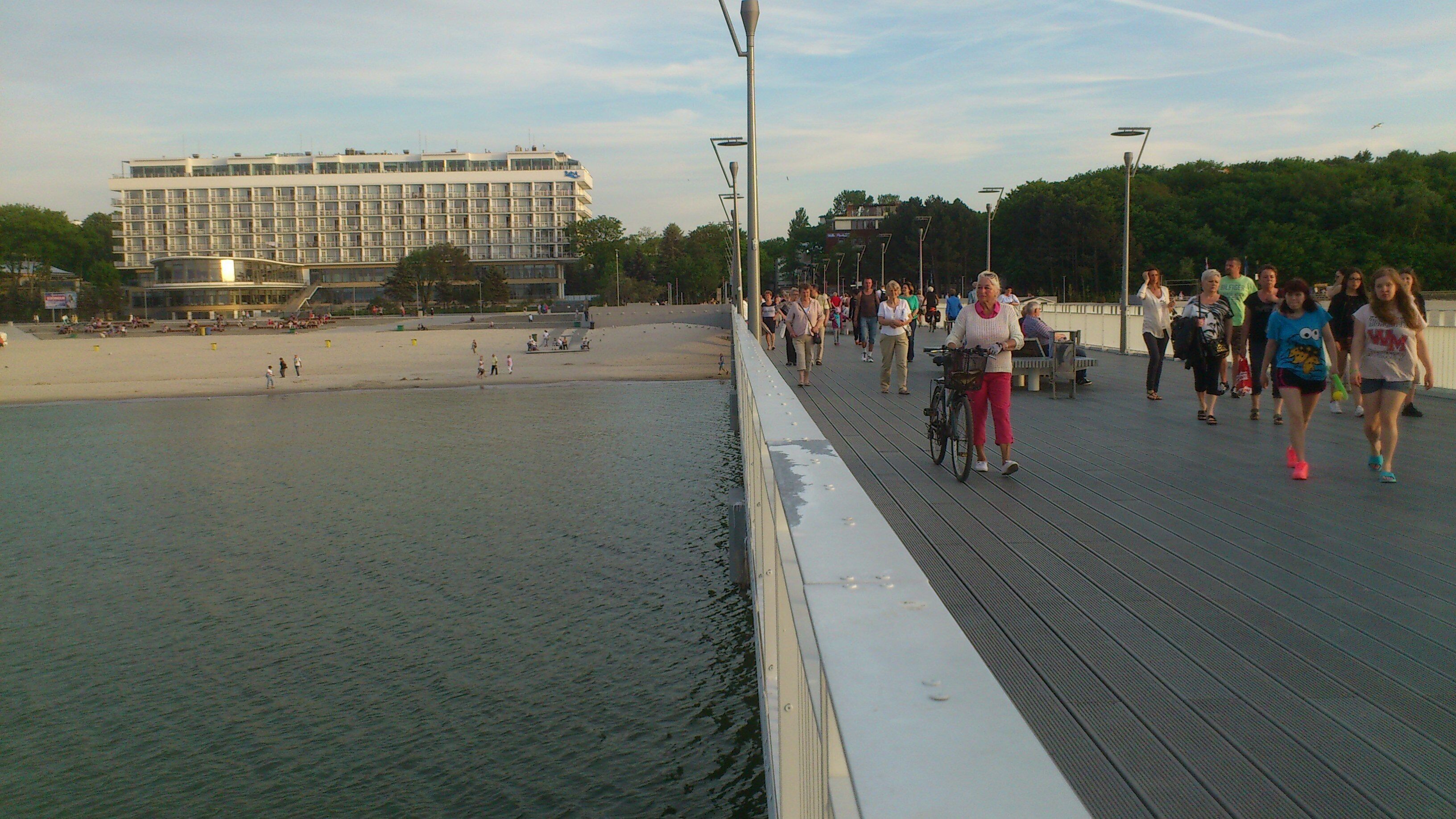 A pedestrian bridge with a view of a beach and a hotel in the background.