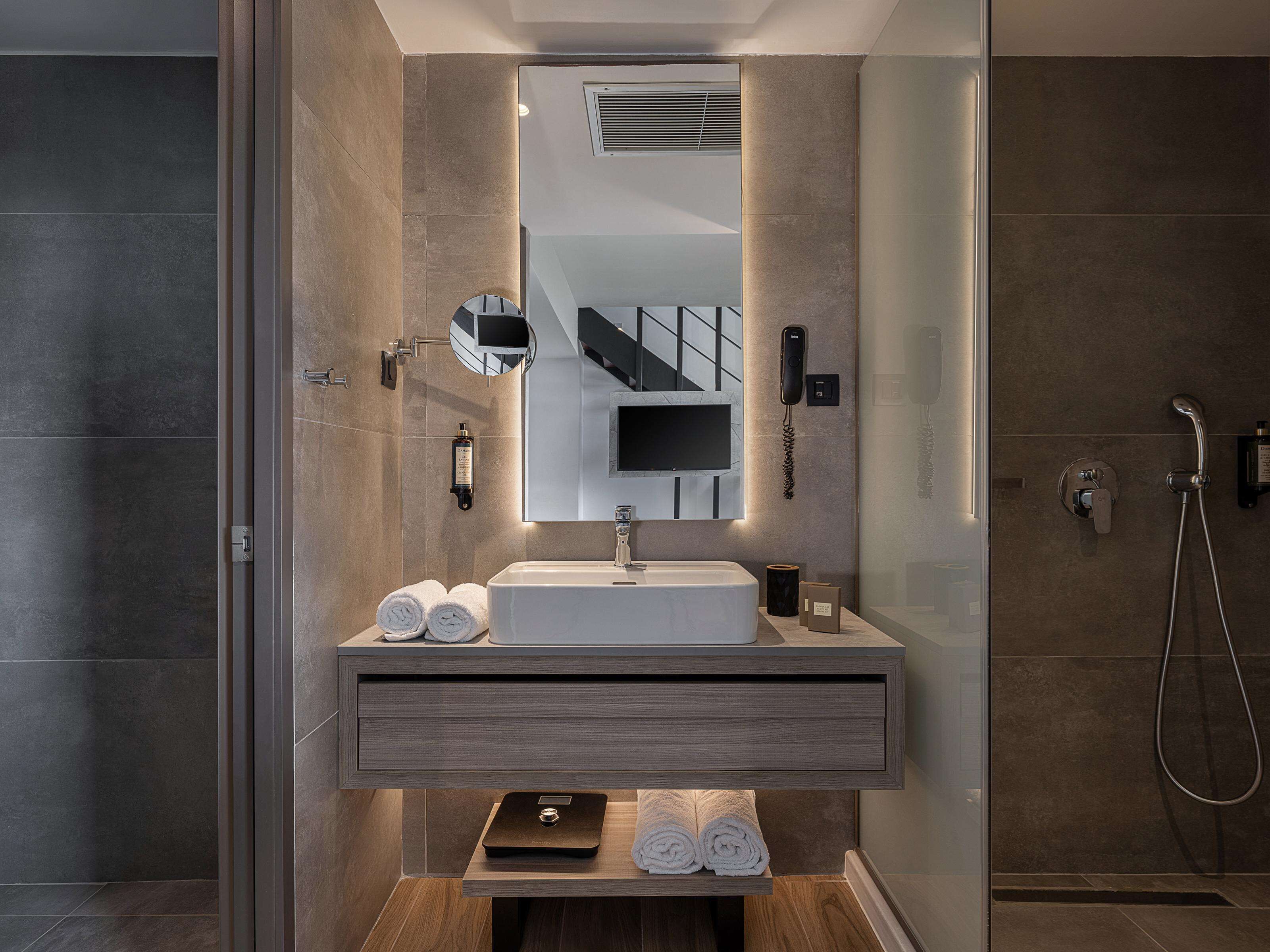 Un baño moderno con un espejo grande, un lavamanos y una ducha.