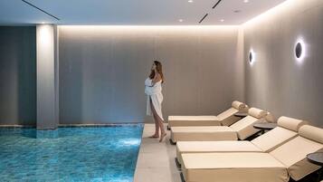 Uma área de spa com piscina, espreguiçadeiras e uma mulher de roupão.