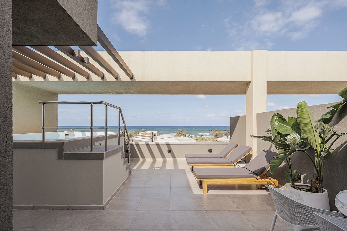 A rooftop terrace with a pool, lounge chairs, and a table.