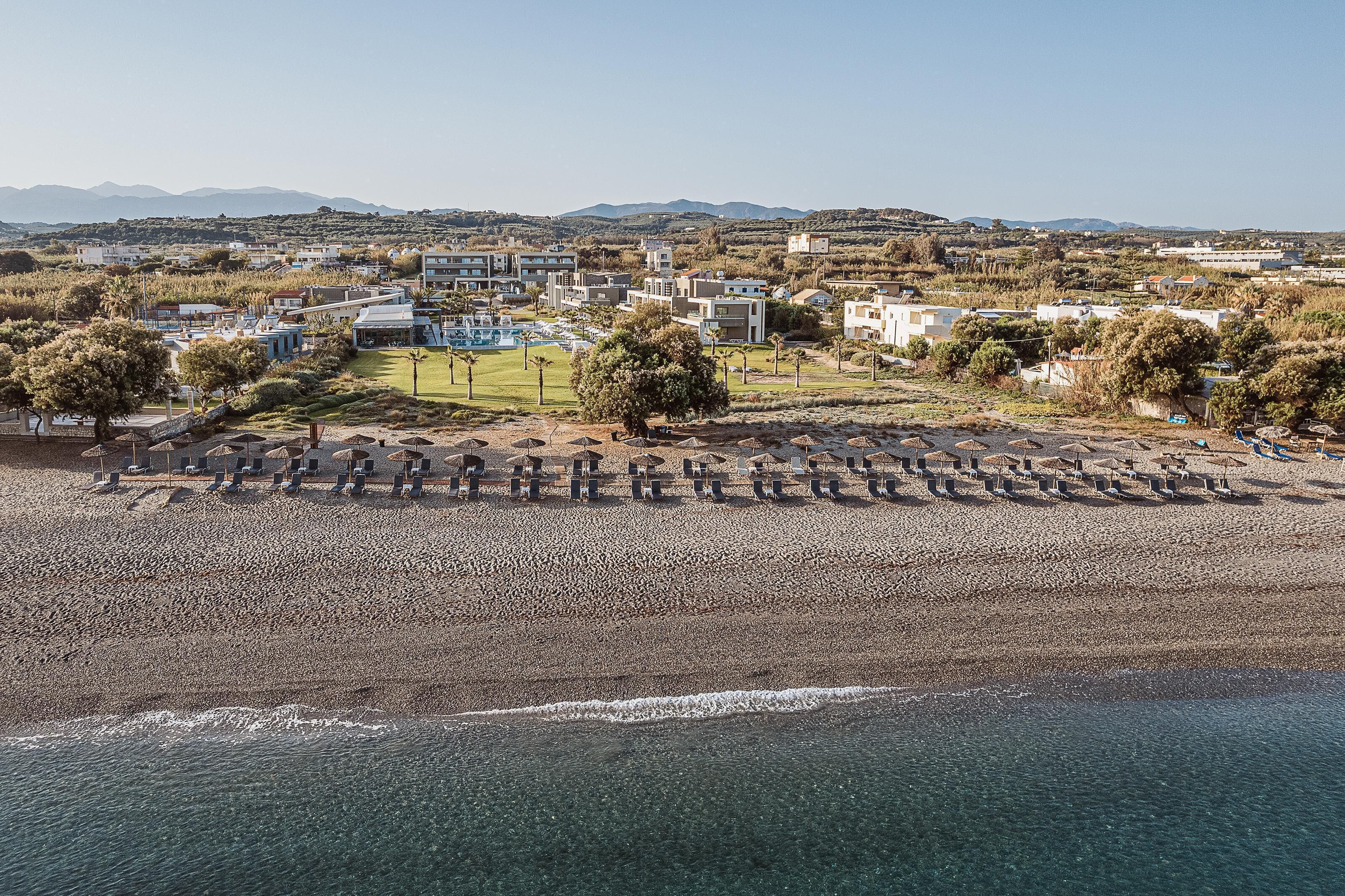 Una zona costiera con spiaggia, piscina e edifici sullo sfondo.